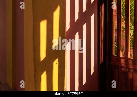 Belle lumière abstraite de couleur et d'ombre en streaming depuis une porte en bois d'une ancienne maison à Pondichéry, Inde. Banque D'Images