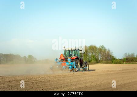 Tracteur labourage dans le champ, poussière de sol sec, travaux agricoles de printemps Banque D'Images