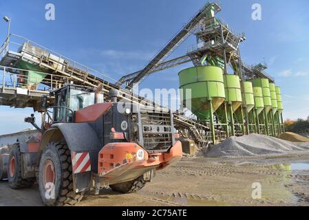 Gravier : chargement de gravier sur un camion par une chargeuse sur pneus et un bâtiment Banque D'Images