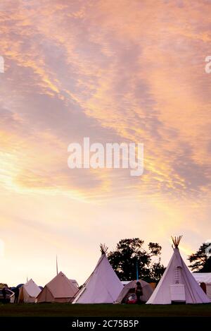 Tipis dans un terrain de glamping avec à un festival de camping au coucher du soleil, Norfolk Banque D'Images