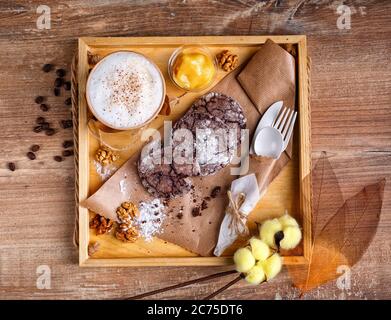 Café à la cannelle, confiture d'orange et biscuits aux pépites de chocolat faits maison. Le dessert se trouve sur du papier kraft et du café dans une tasse de papier. Banque D'Images