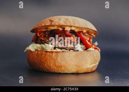 Circulaire Burger. Hamburger au fromage avec viande grillée, fromage, salade et rondelles d'oignon. Gros plan de délicieux hamburgers maison frais sur fond bleu écorce Banque D'Images