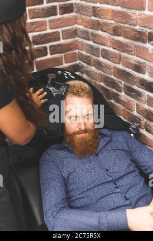 Jeune homme avec une coupe de cheveux tendance au salon de coiffure. Le coiffeur lave la tête du client. Concept barbershop. Banque D'Images