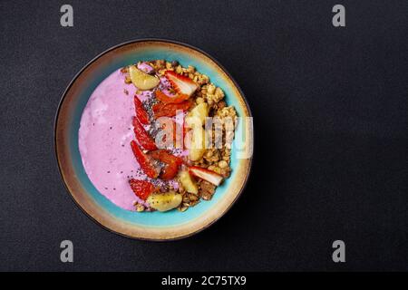 Bol avec smoothie aux baies, granola, graines de chia, banane, noix, fraises Banque D'Images