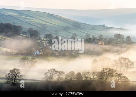 Le beau village de Appletreewick dans le Yorkshire Dales est entouré de brouillard flottant sur un matin d'hiver que le soleil se lève sur les collines. Banque D'Images