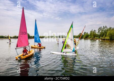 Les jeunes apprennent à faire de la planche à voile et à naviguer sur l'un des lacs du parc aquatique Cotswold. Banque D'Images