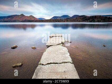 Une soirée calme, ciel nuageux à l'Isthme Bay (Derwent Water) comme les eaux calmes du lac entourent l'ancienne jetée en béton en ruine. Banque D'Images