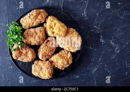 Gros plan de côtelettes de porc japonaises, HireKatsu sur une plaque noire sur une table en béton, vue horizontale depuis le dessus, plat, espace libre Banque D'Images