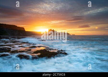 Le Château de Tantallon est découpé par le coucher de soleil sur la falaise au-dessus de la plage de Seacliff, East Lothian, Ecosse, comme les vagues déferlent sur la plage ci-dessous. Banque D'Images