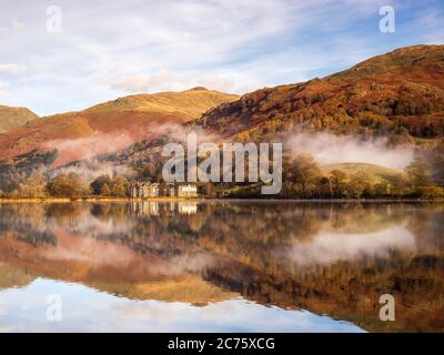 La dernière de la brume d'une inversion de température s'accroche sur le côté de l'abat par Grasmere comme the Daffodil Hotel se reflète dans le miroir du lac calme. Banque D'Images