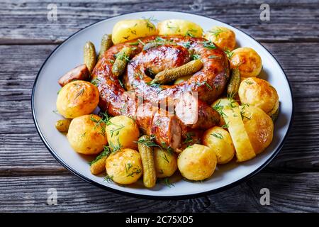 Plat allemand à l'ancienne : jeunes pommes de terre bouillies et frites, servies avec des saucisses de porc et des concombres marinés, saupoudrées d'aneth frais, servis sur une assiette Banque D'Images