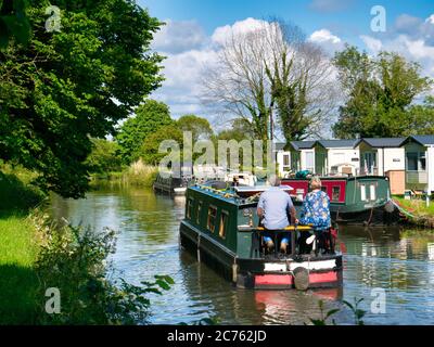 Vacanciers sur un bateau à narrowboat qui navigue sur le canal Leeds-Liverpool dans le Lancashire, paisible et rural. Pris par une journée ensoleillée en été. Banque D'Images