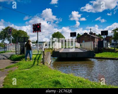 Un propriétaire de bateau à rames ouvre le pont électrique à bascule de New Lane sur le canal Leeds-Liverpool près de Burscough dans Lancashire, Royaume-Uni. Pris un jour ensoleillé Banque D'Images