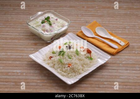 Légumes Pulav ou Pulao, faits à base de riz basmathi, légumes et épices indiennes.Raita comme plat d'accompagnement disposé dans un plat blanc carré de table avec couleur bois Banque D'Images