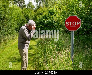 Panneau d'avertissement original Stop inquiétante sur le sentier de campagne avec un homme senior qui semble inquiet, Gifford, East Lothian, Écosse, Royaume-Uni Banque D'Images