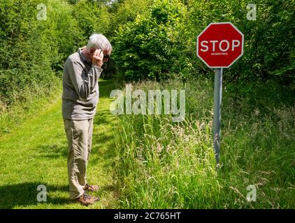 Panneau d'avertissement original Stop inquiétante sur le sentier de campagne avec un homme senior qui semble inquiet, Gifford, East Lothian, Écosse, Royaume-Uni Banque D'Images