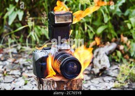 Appareil photo brûlé dans un incendie de forêt, le touriste a subi des pertes. Le matériel photo en feu pendant une catastrophe dans un camping. Allumage de biens en cas d'urgence Banque D'Images