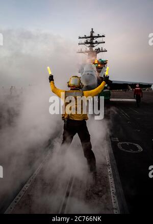 Un marin de la Marine américaine dirige un avion de chasse F/A-18e Super Hornet sur un catapulte sur le pont de vol du porte-avions de la classe Nimitz USS Dwight D. Eisenhower pendant les opérations du 26 juin 2020 dans la mer d'Arabie. Banque D'Images