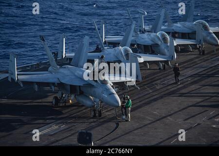 Les marins de la Marine américaine prennent des lectures diagnostiques d'un Super Hornet F/A-18e affecté aux Tomcatters de Strike Fighter Squadron 31, pendant l'entretien de routine à bord du porte-avions USS Theodore Roosevelt de la classe Nimitz pendant les opérations du 30 juin 2020 dans l'océan Pacifique oriental. Banque D'Images