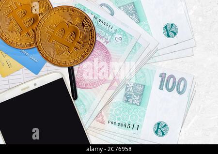 100 billets de korun tchèques et bitcoins dorés avec smartphone et cartes de crédit. Concept d'investissement en crypto-monnaie. Opérations d'exploitation minière ou de commerce de crypto Banque D'Images