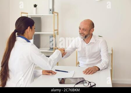 Sourire mature homme patient fait le médecin serrer la main au bureau de la clinique Banque D'Images