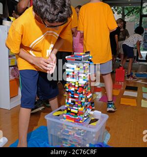 Camp de jour. Brooklyn, NY. UN camp spécialisé dans la technologie et la robotique. Garçon travaillant avec des blocs lego pour construire une tour. Banque D'Images