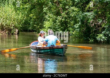 Un couple enoyant un voyage en bateau à rames sur le canal de Chichester, Chichester, West Sussex, Royaume-Uni. Banque D'Images