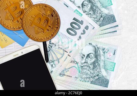 100 billets de korun tchèques et bitcoins dorés avec smartphone et cartes de crédit. Concept d'investissement en crypto-monnaie. Opérations d'exploitation minière ou de commerce de crypto Banque D'Images