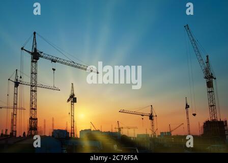 Paysage industriel avec silhouettes de grues au coucher du soleil Banque D'Images