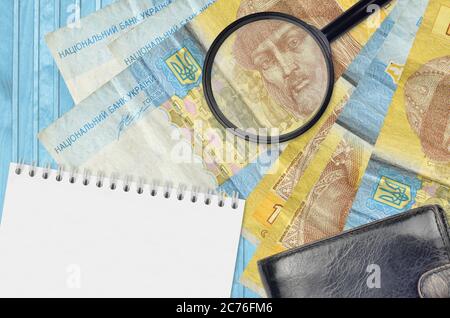 1 billets de hryvnia ukrainien et loupe avec sac à main noir et bloc-notes. Concept de fausse monnaie. Recherchez des différences dans les détails sur l'argent Banque D'Images