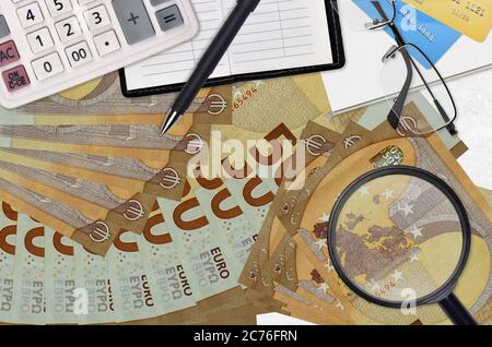 50 euros de factures et calculatrice avec lunettes et stylo. Concept de saison de paiement d'impôt ou solutions d'investissement. Recherche d'un emploi avec des salaires élevés Banque D'Images
