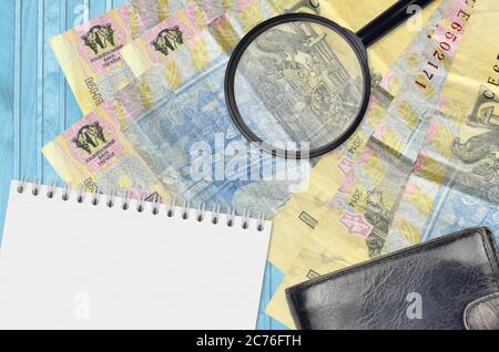 1 billets de hryvnia ukrainien et loupe avec sac à main noir et bloc-notes. Concept de fausse monnaie. Recherchez des différences dans les détails sur l'argent Banque D'Images