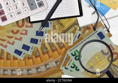 50 euros de factures et calculatrice avec lunettes et stylo. Concept de saison de paiement d'impôt ou solutions d'investissement. Recherche d'un emploi avec des salaires élevés Banque D'Images