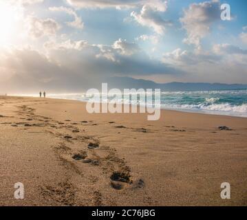 Belle plage avec des empreintes dans le sable. Les amateurs de marche sur la plage au coucher du soleil et empreintes de pieds laissant sur la plage. Silhouettes de coup Banque D'Images