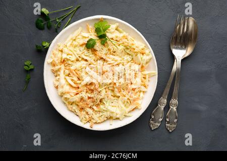 Salade de coleslaw fraîche de chou râpé, carotte et mayonnaise sur fond de béton noir. Vue de dessus. Banque D'Images