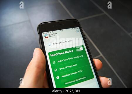 Corona Warn App du gouvernement fédéral allemand sur un smartphone tenu dans la main d'un homme. Développé par SAP et Deutsche Telekom. Banque D'Images