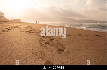 Belle plage avec des empreintes dans le sable. Les amateurs de marche sur la plage au coucher du soleil et empreintes de pieds laissant sur la plage. Silhouettes de coup Banque D'Images