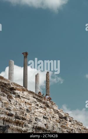 Couple assis sur le dessus de ruines dans Tyr. Les gens se reposant après l'excursion le long de la nécropole au Liban. Visite de célèbre endroit. Patrimoine mondial. Actif Banque D'Images