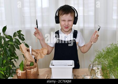 Le garçon est engagé dans la plantation des hyacinthes. Il a serré les yeux et fait la démonstration de matériel de jardinage dans les deux mains. Banque D'Images