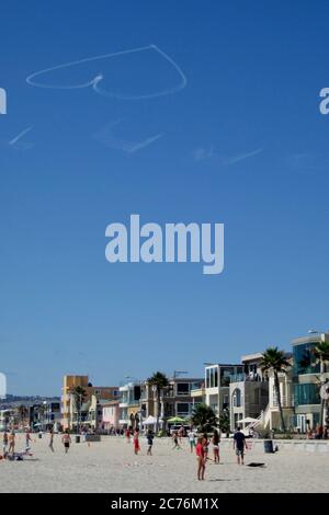 Un cœur est dessiné par les contrailles d’un avion contre un ciel bleu à Mission Beach, en Californie. Banque D'Images