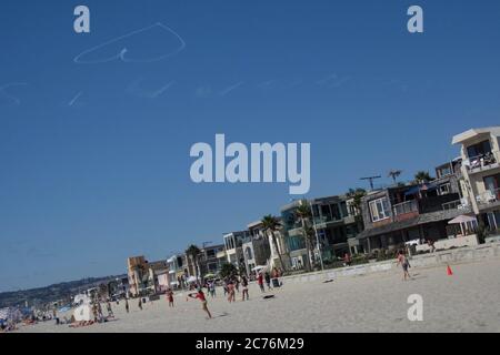 Un cœur est dessiné par les contrailles d’un avion contre un ciel bleu à Mission Beach, en Californie. Banque D'Images