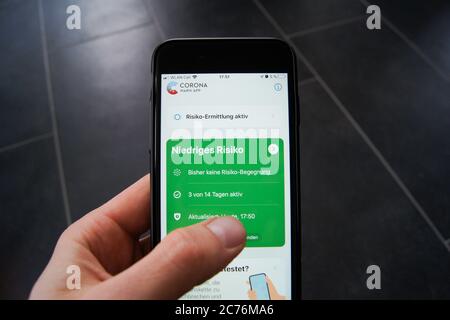 Corona Warn App du gouvernement fédéral allemand sur un smartphone tenu dans la main d'un homme. Développé par SAP et Deutsche Telekom. Banque D'Images