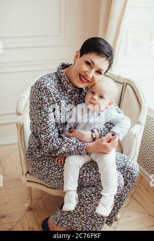 Portrait d'un bébé garçon souriant assis sur les genoux de sa grand-mère Banque D'Images