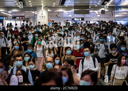 Les passagers portant des masques de protection traversent la gare de Hong Kong. Le gouvernement de Hong Kong impose de nouvelles mesures strictes de distanciation sociale et le port obligatoire de masques pour les personnes utilisant les transports publics. Banque D'Images