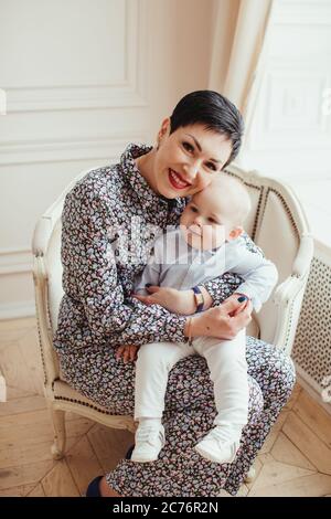 Portrait d'un bébé garçon souriant assis sur les genoux de sa grand-mère Banque D'Images