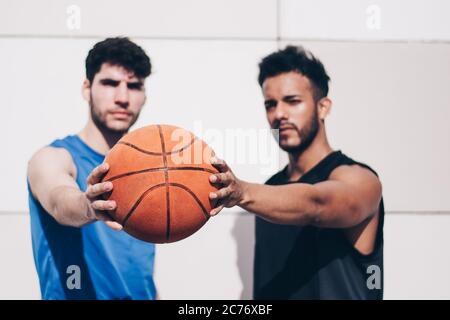 deux joueurs de basket-ball de différentes courses tiennent une balle ensemble Banque D'Images