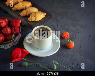 Fond vintage avec des coquelicots rouges i, une tasse de café, des fraises dans une assiette et des croissants sur un plateau en bois Banque D'Images