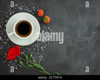 Tasse de café sur une table de texture avec fleurs de pavot, fraises et sucre de poulet saupoudrés Banque D'Images