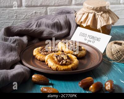 Romantique matin encore la vie dans un style rustique avec des biscuits, du miel et des dates sur un fond en bois turquoise, avec une carte blanche pour l'inscription. Banque D'Images