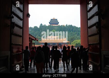 Un groupe de touristes entrant dans la porte de la Cité interdite à Beijing, en Chine, avec une personne debout dans la direction opposée en posant Banque D'Images